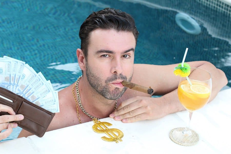 arrogant man swimming in the pool with money and cocktail