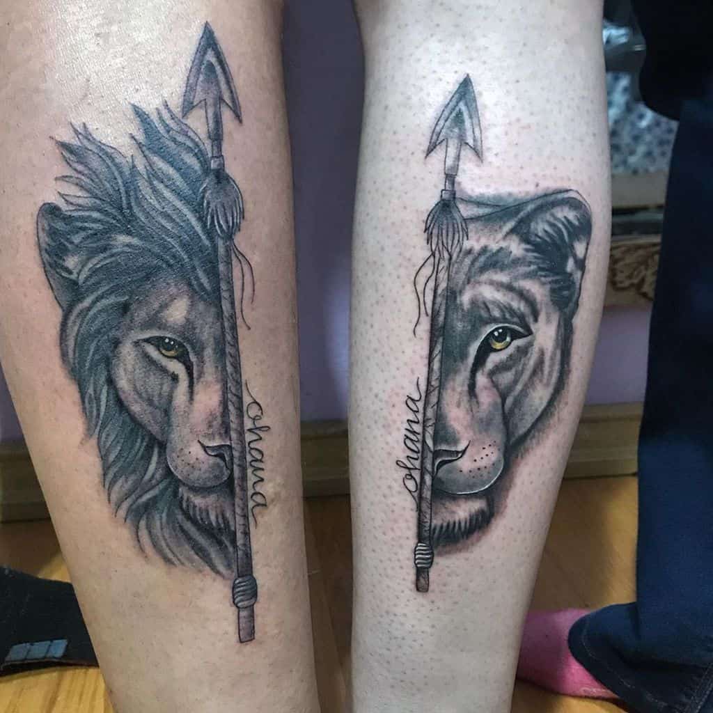 Matching lion and lioness tattoos with a spear and 'Ohana' text, symbolizing strength, unity, and family bonds.