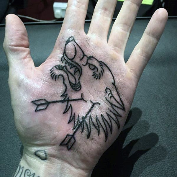 A palm with a wolf head tattoo drawn in black ink