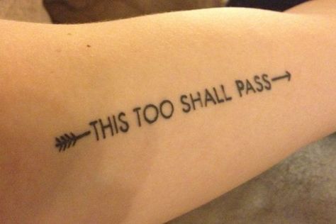 A "This Too Shall Pass" tattoo with arrows at each end, displayed on a person's forearm.