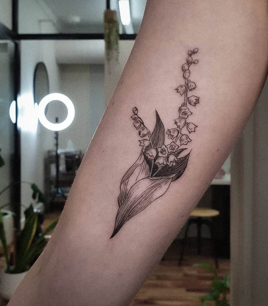 Elegant black ink Lily of the Valley tattoo, featuring delicate bell-shaped flowers and detailed leaves in a fine line style