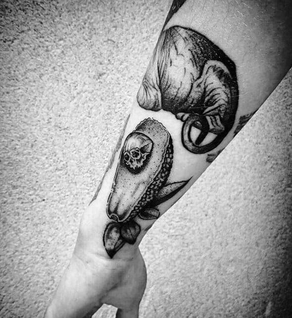 Realistic black and grey avocado tattoo with a skull-shaped pit, placed on the forearm for a dark, edgy twist.