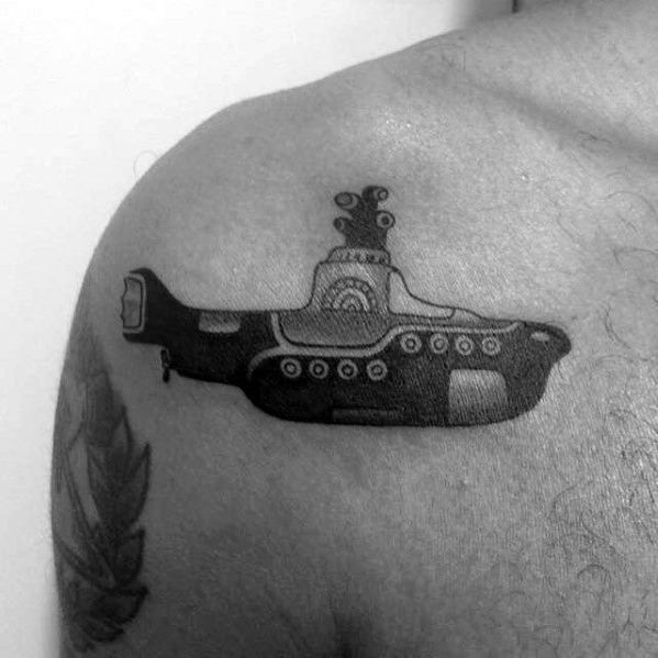 Black and gray tattoo of the iconic Yellow Submarine from The Beatles, placed on the shoulder with stylized, cartoonish detailing.