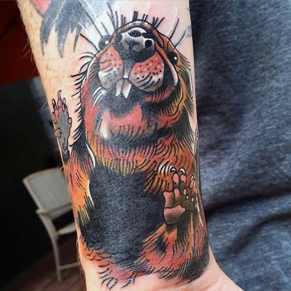 Realistic beaver tattoo on forearm with rich brown tones, detailed fur texture, and playful expression showing large teeth.