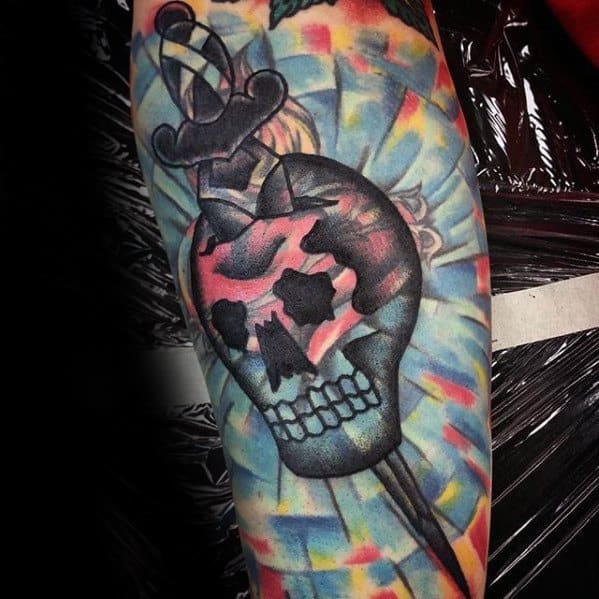 Blast over tattoo featuring a skull pierced by a dagger with a colorful geometric background