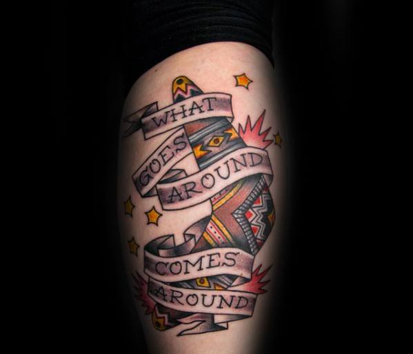 Colorful boomerang tattoo with stars, bursts, and a ribbon reading what goes around comes around wrapped around it.
