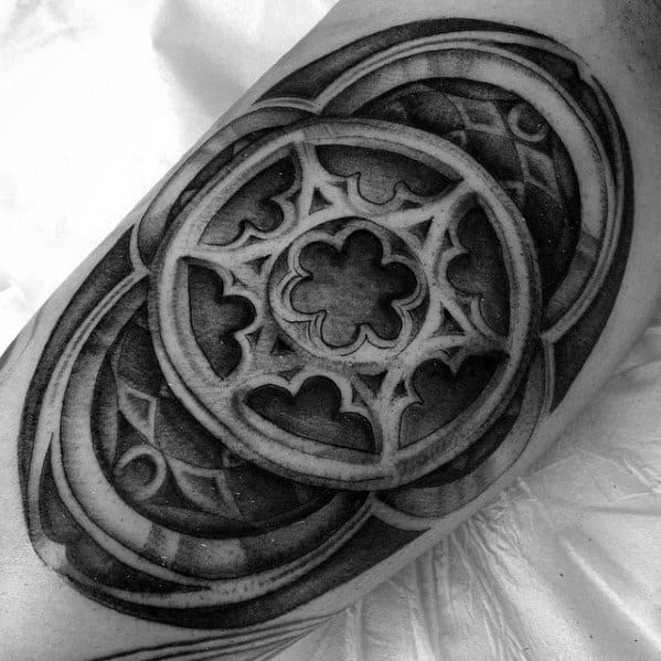 Black and grey tattoo of a gothic cathedral rose window design with intricate arches and layered 3D shading.