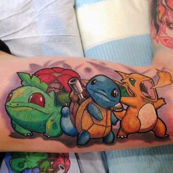 Vibrant tattoo of Bulbasaur, Blastoise, and Charizard in action poses on forearm, featuring bold outlines and vivid colors.