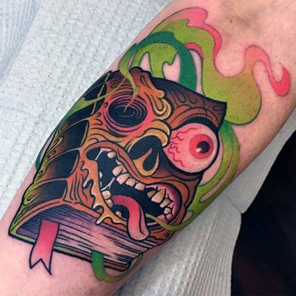 Colorful Evil Dead tattoo of the Necronomicon with a crazed face, bulging eye, sharp teeth, and green-pink smoke swirling around.
