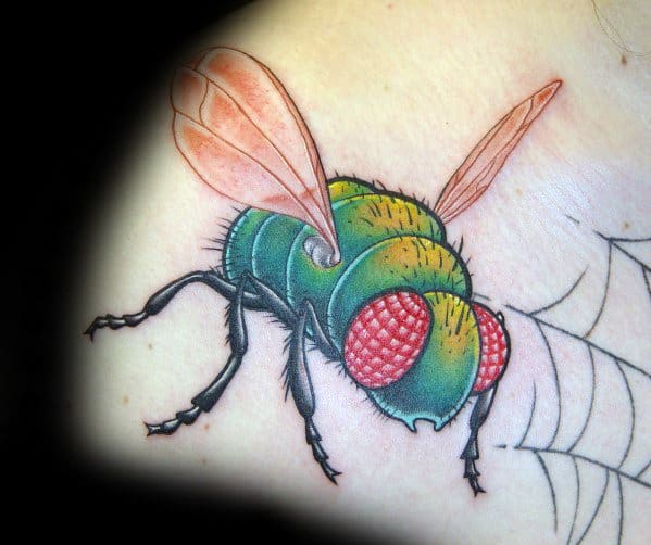 Colorful fly tattoo with vibrant green body, large red eyes, and translucent wings, perched on a spiderweb outline.