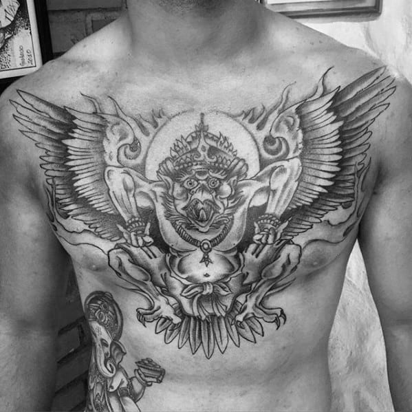 Garuda tattoo design spanning the chest, featuring a powerful winged deity with fierce expression, crown, and symmetrical detailing.