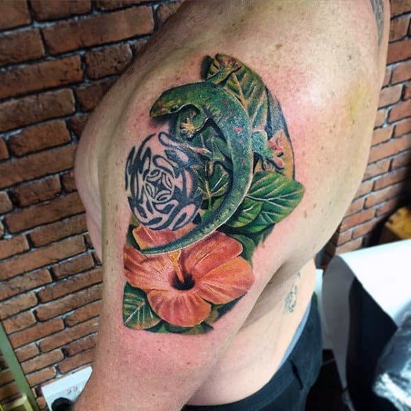Colorful gecko tattoo on upper arm with tribal circle, green leaves, and a large orange hibiscus flower.