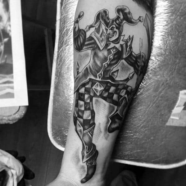 A black and gray tattoo of a jester in motion, wearing a checkered outfit and juggling, showcasing a playful yet intense expression.