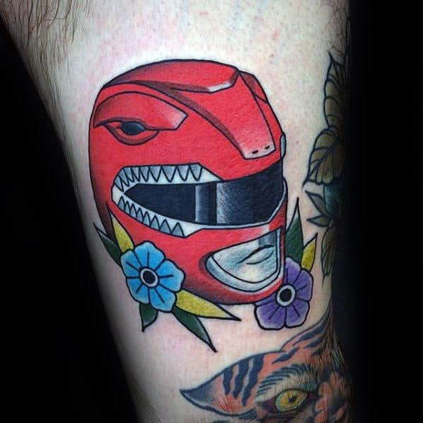 Bold Red Power Ranger helmet tattoo with vibrant flowers and sharp lines, blending pop art and traditional styles.
