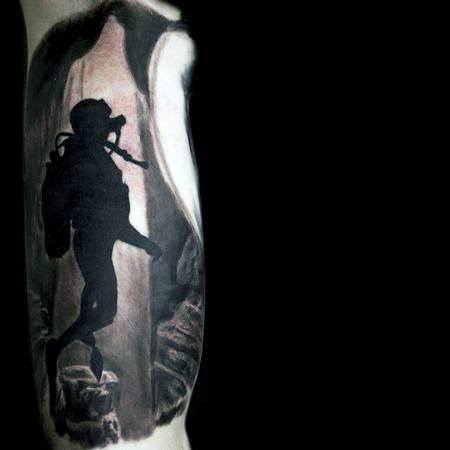 Dark and atmospheric tattoo of a scuba diver exploring an underwater cave, with light shining from the cave opening above.
