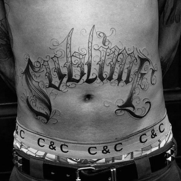 Large "Sublime" tattoo in ornate script spanning the stomach, done in bold black and grey ink with decorative swirls.