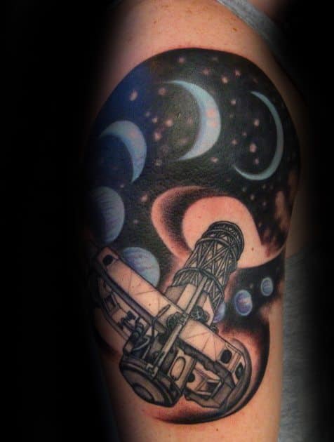 Space-themed tattoo with a telescope and celestial wonders on the arm