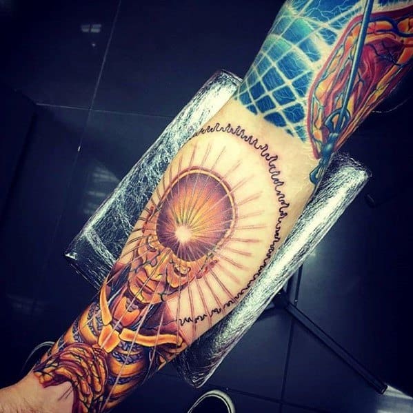 Tool-inspired forearm tattoo of a radiant skeletal figure with a glowing head, surrounded by waves and geometric patterns.