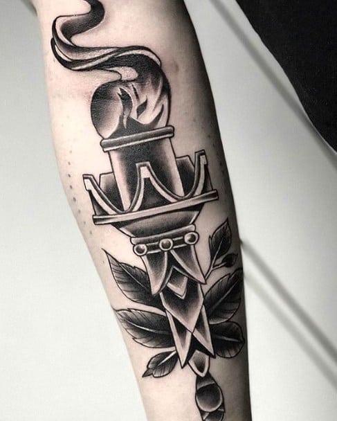 Black and grey torch tattoo with smooth shading, stylized flames, and leafy details wrapping around the lower part.