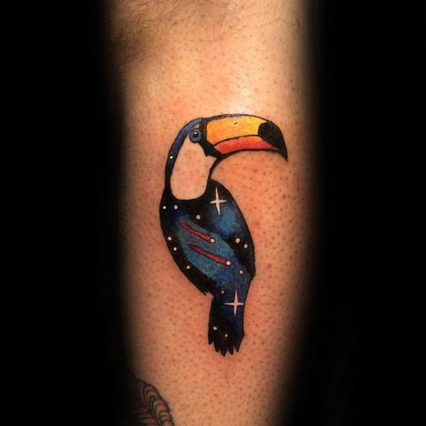 Minimalist toucan tattoo with a cosmic-themed body, featuring stars and galaxies in a deep blue background.