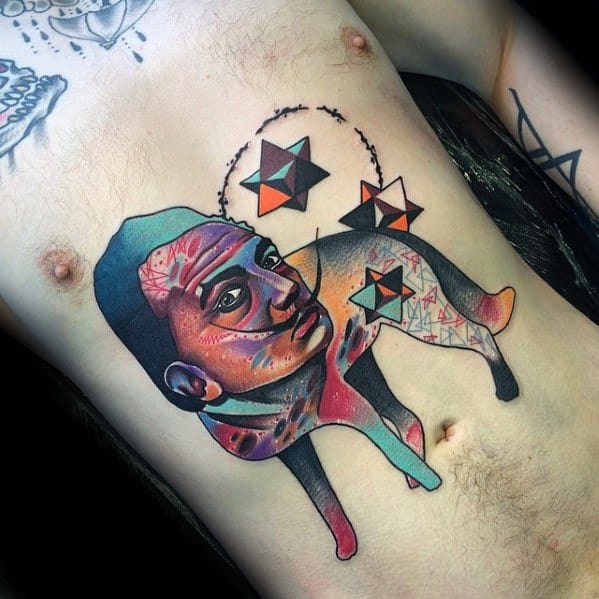 Abstract rib tattoo of a surreal human-animal hybrid figure with a colorful face and floating geometric stars in orbit above.
