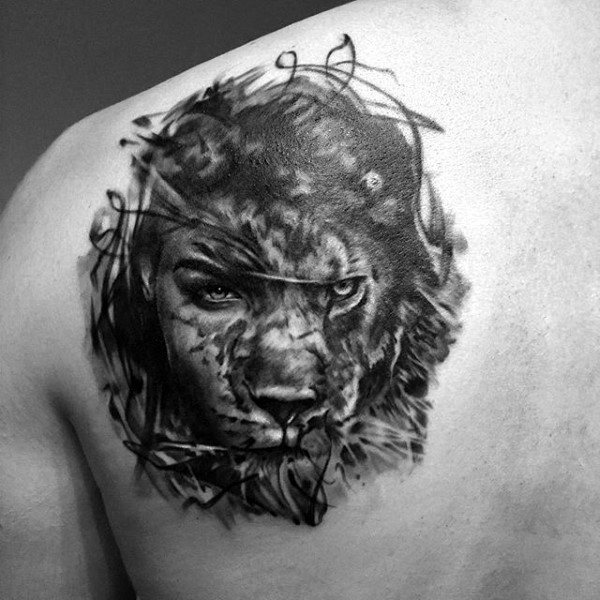 Black and white tattoo of a fierce lion's face on a person's upper back