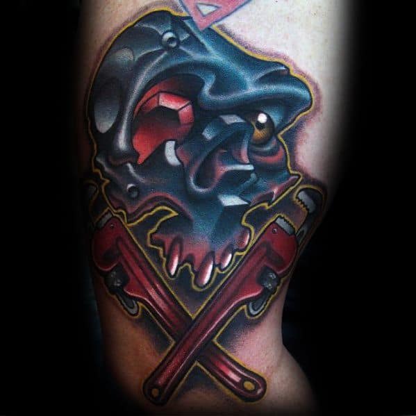 Tattoo of a metallic skull with glowing red eyes above two crossed red pipe wrenches, in a bold and vivid color style.