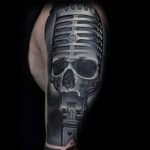 Tattoo of a vintage microphone with a skull design, inked on an upper arm