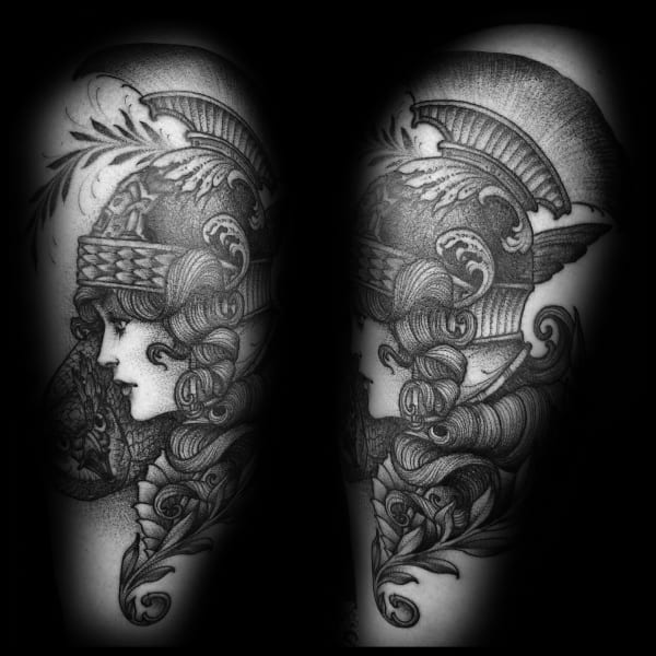 Detailed Athena tattoo with a side-profile view, featuring ornate helmet, flowing curls, and leafy decorative elements in black ink