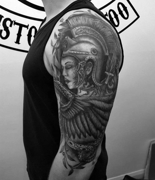 Full-sleeve Athena tattoo with intricate helmet, detailed facial features, and large wing design in bold black and grey realism