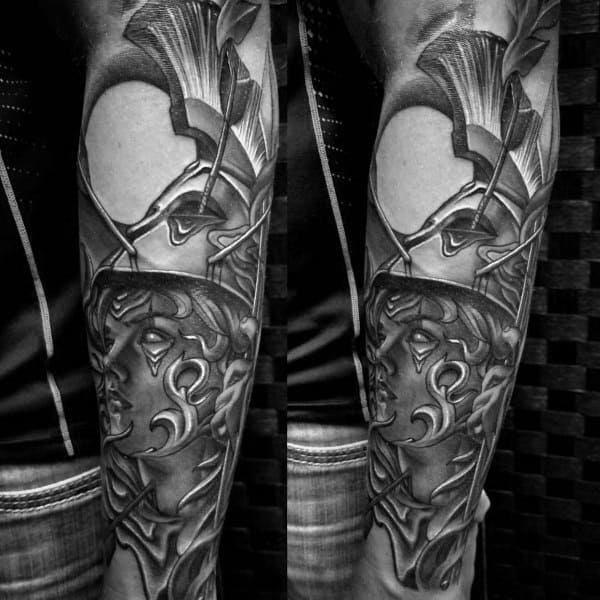 Bold Athena tattoo sleeve with sharp geometric armor, stylized helmet, and sculpted face in high-contrast black and grey style