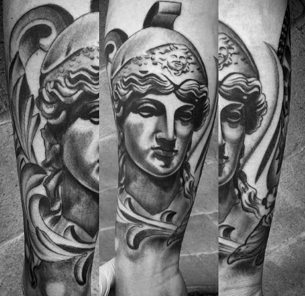 Classic Athena tattoo with a marble statue look, featuring a crested helmet and soft black and grey shading on the forearm