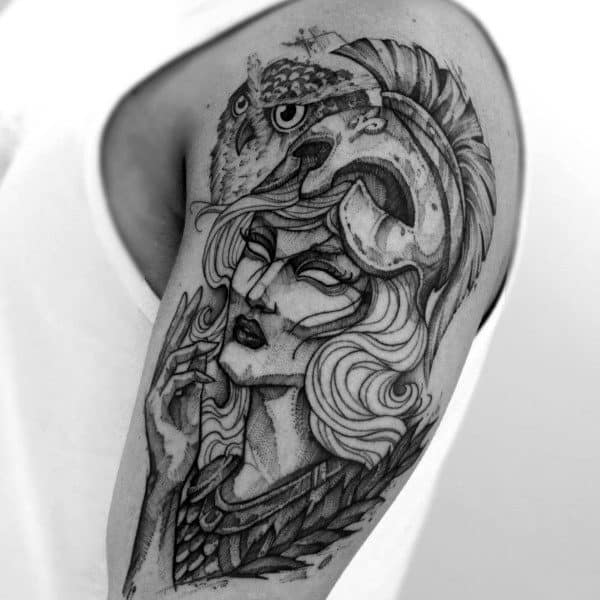 Black and white tattoo of Athena in a helmet with an owl on her shoulder, on an upper arm