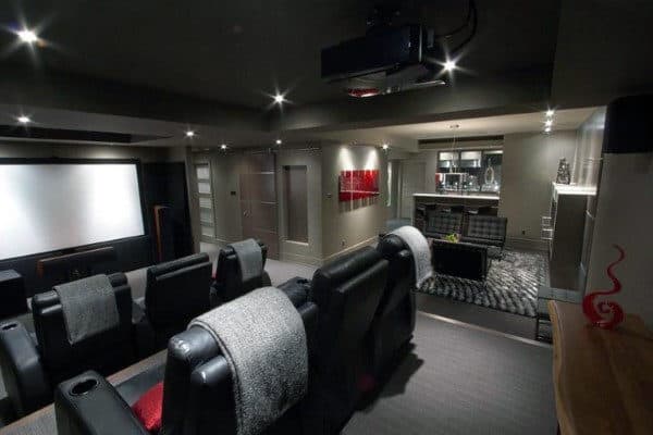Home theater with plush reclining seats, large screen, and modern decor; dim lighting creates a cozy home movie atmosphere