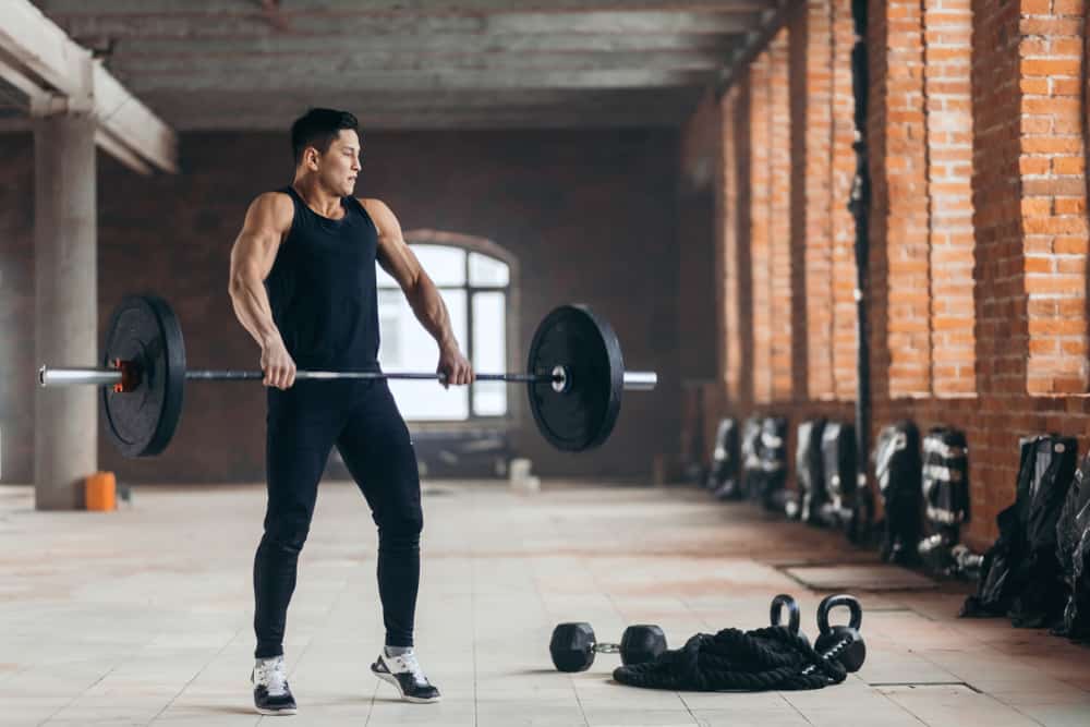 man attempts to lift the weight in a large building hall