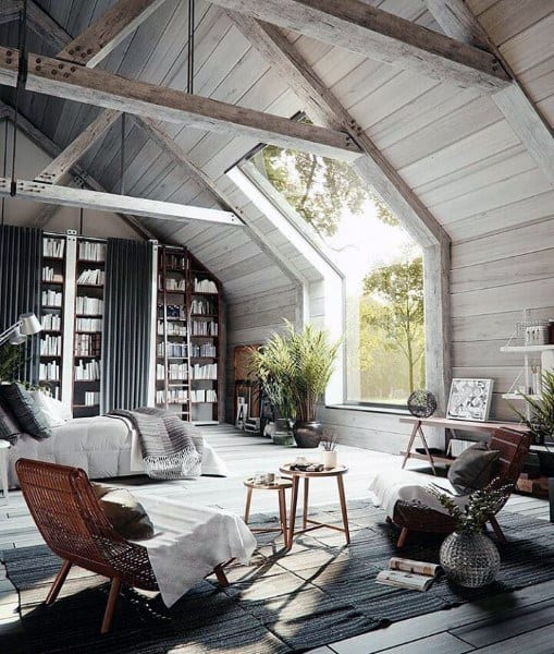 Cozy attic living room with wooden beams, bookshelves, seating area, a large window, and lush plants