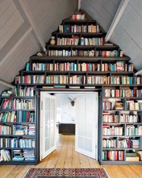 A cozy library with a bookshelf-filled doorway surrounded by books