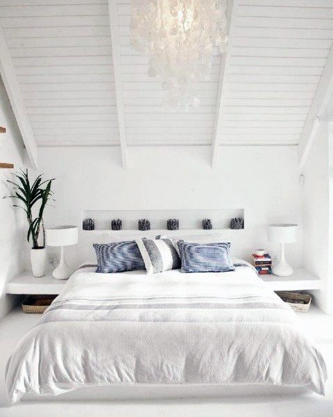 Bright attic bedroom with all-white decor, vaulted ceiling, and hanging capiz shell chandelier.