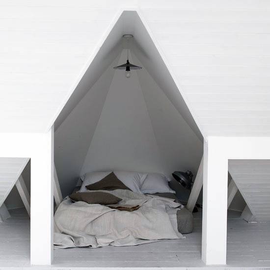 Cozy bed in a minimalist attic space with white walls and muted bedding