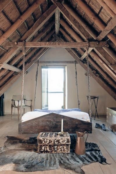 Vintage hanging bed with wooden frame, rustic ropes, and exposed beams in a cozy attic space.