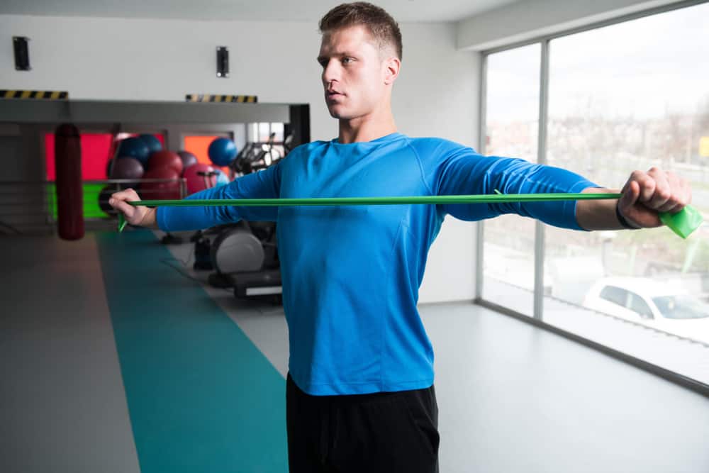 attractive man exercising with resistance band in gym