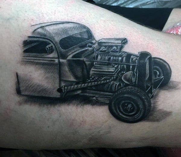 Tattoo of a black and white hot rod car engine and wheel on skin