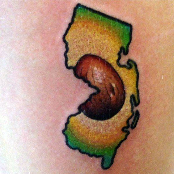 Creative avocado tattoo in the shape of New Jersey, with a detailed brown pit and bold color blending inside the state outline.