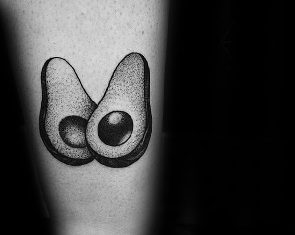 Blackwork avocado tattoo featuring two halves positioned to resemble a pair of breasts, with dotted shading and bold outlines.