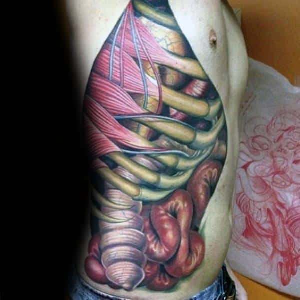 Hyper-realistic anatomical tattoo on the side torso, showing exposed ribs, muscles, and intestines in vivid red, yellow, and flesh tones.