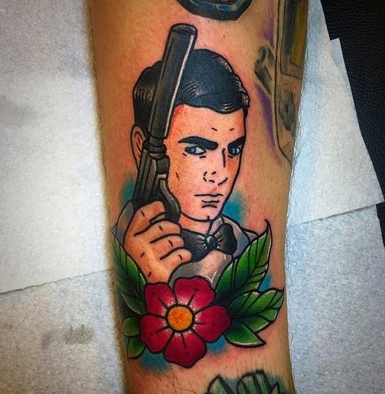 Bold Archer-inspired tattoo featuring a classic spy with a revolver, crisp outlines, vibrant colors, and a floral accent.