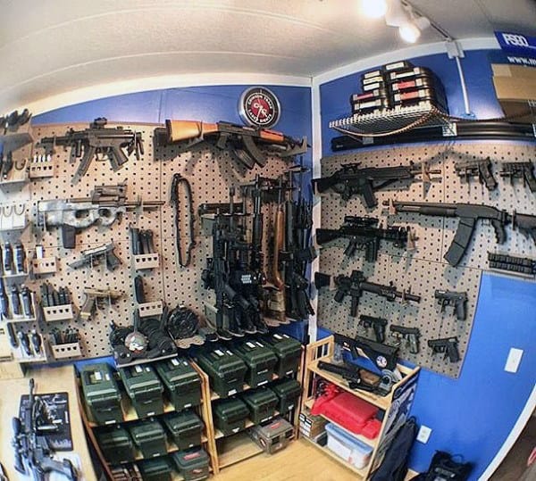 Gun room with blue walls, pegboard displaying firearms, ammo boxes, and shooting accessories.