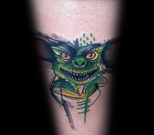 Gremlin tattoo with vibrant green tones, red eyes, and a sketch-style design, creating a bold and edgy look.
