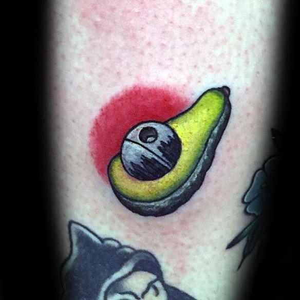 Unique avocado tattoo featuring the Death Star as the pit, with a red circle background blending Star Wars and food-themed art.