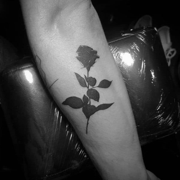 Black rose tattoo on a person's forearm